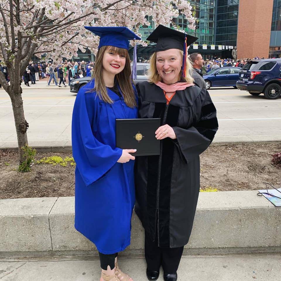 Lauren Glomb holding her GVSU diploma, standing next to Dr. Vavrikova.